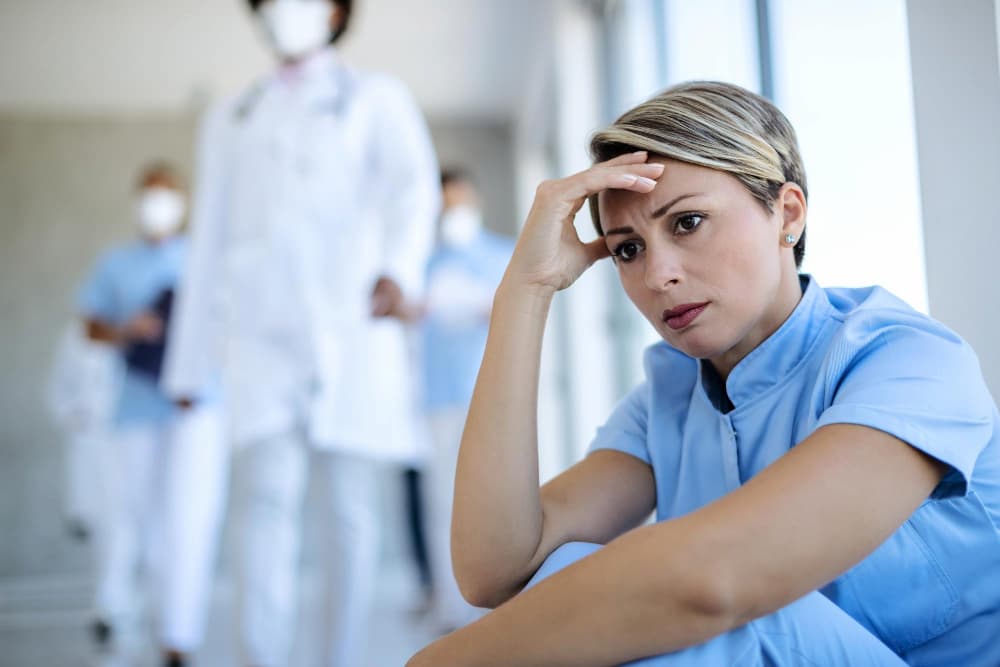 Enfermera angustiada sentada en un pasillo y pensando en algo