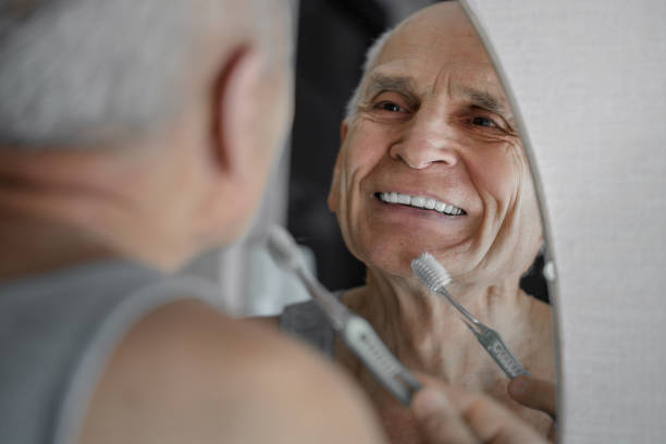 Hombre mayor frente al espejo lavándose los dientes
