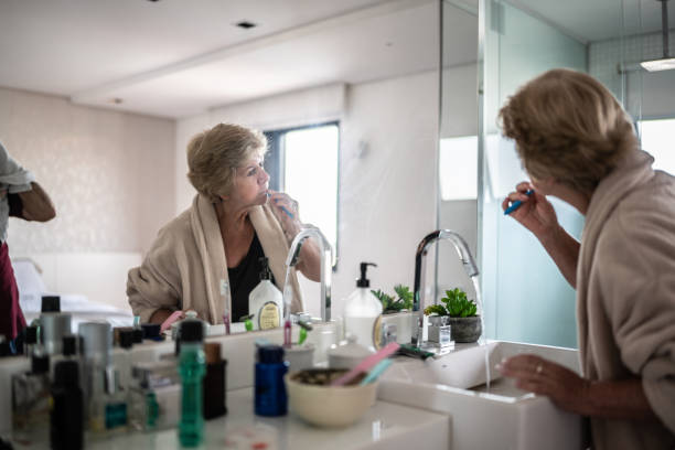 mujer mayor frente al espejo lavándose los dientes