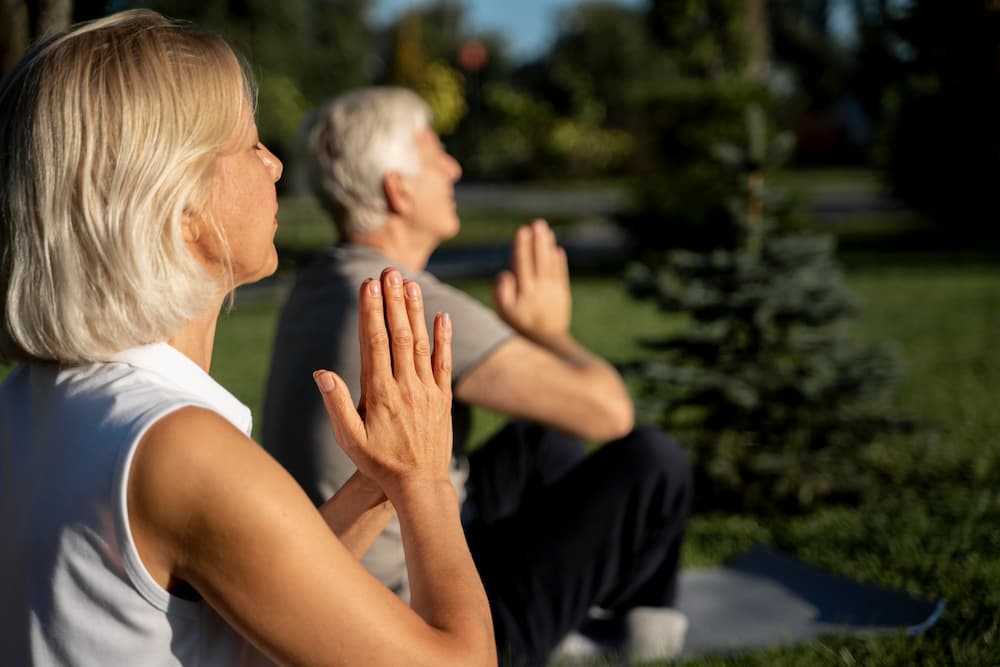 Ancianos practicando yoga al aire libre para reducir la ansiedad