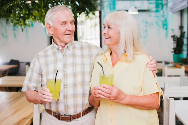 Pareja de ancianos paseando disfrutando de unos batidos
