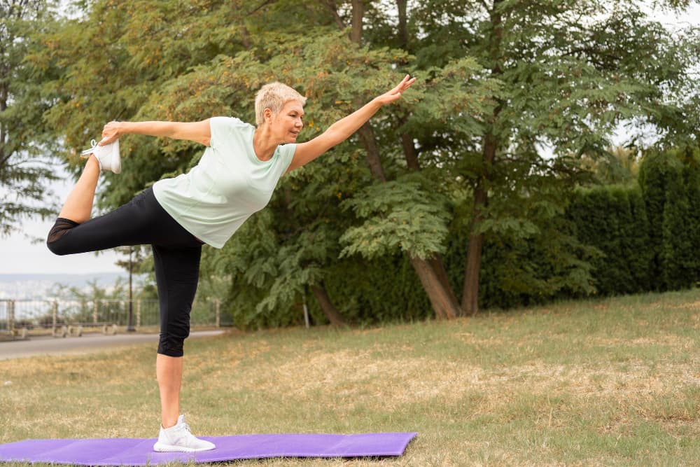mujer mayor haciendo yoga al aire libre